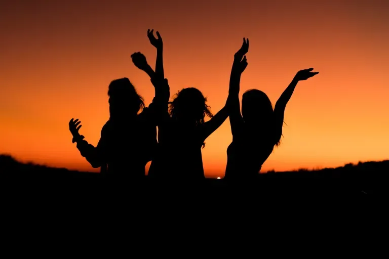 three friends with their arms raised in the air