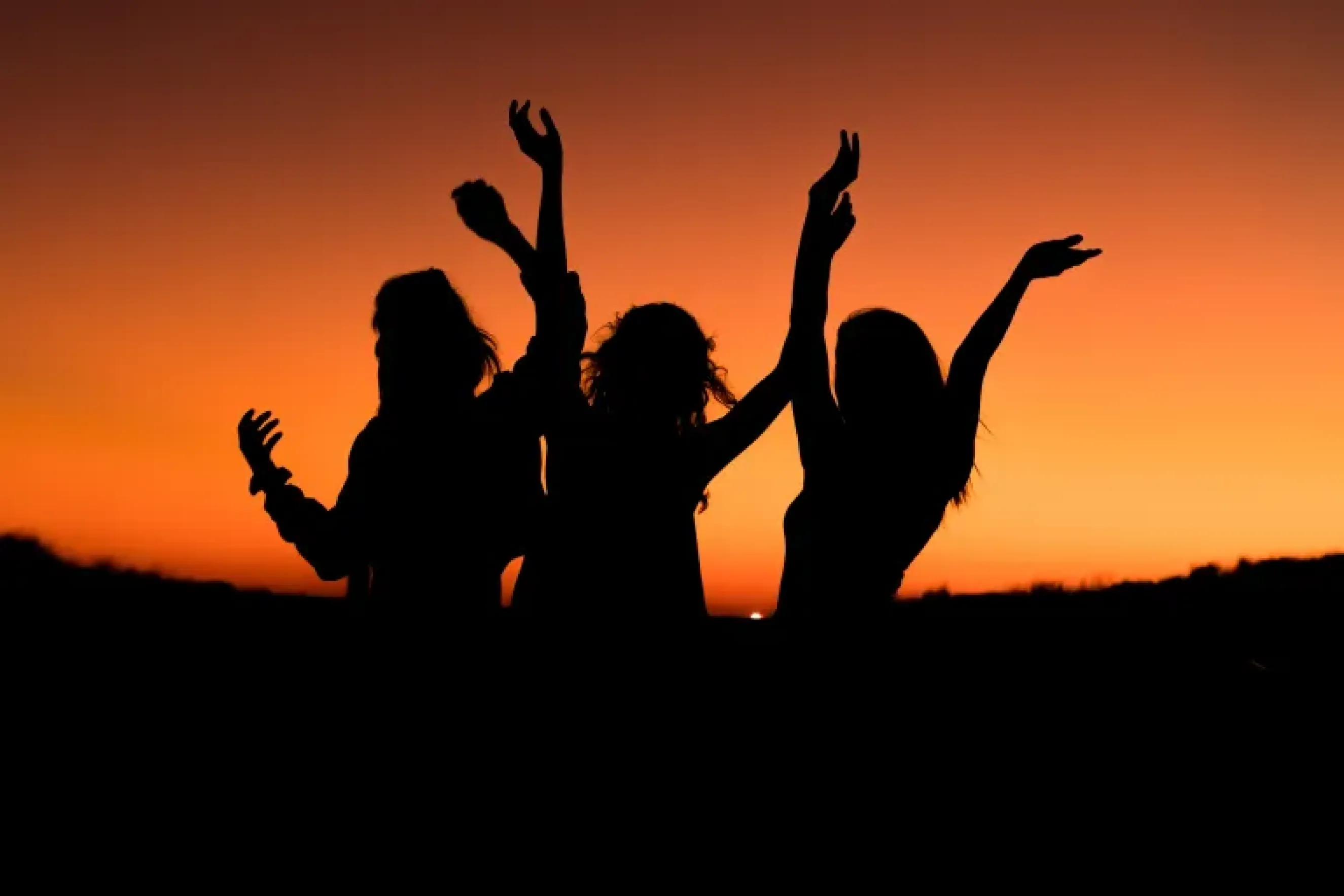three friends with their arms raised in the air